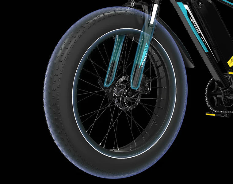 Close-up of a fat tire on an electric bicycle, with thick treads, disc brake, and black and blue suspension fork against a black background.
