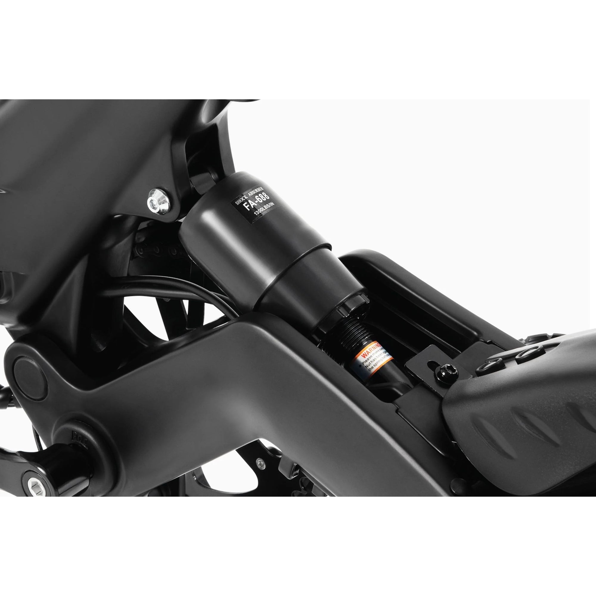 Close-up view of a black rear shock absorber attached to the frame of a bicycle, showing detailed suspension components and part of the bike’s rear wheel and seat tube.