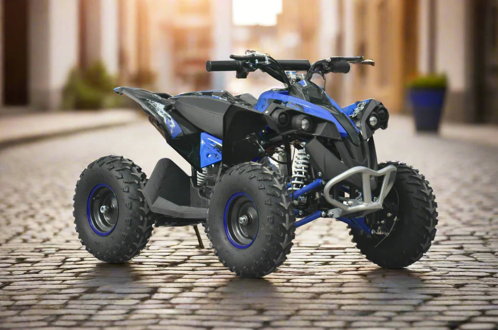 Blue and black all-terrain quad bike with large knobby tires on a cobblestone street in soft light