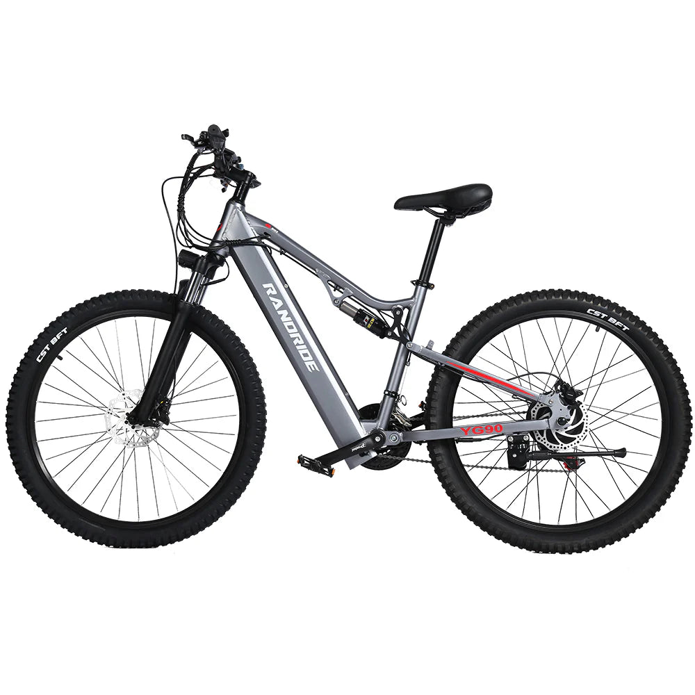 The Randride YX90A Electric Mountain Bike features a silver and black slanted frame, full suspension, thick tires, and both front and rear suspension. The Randride brand name is visible on the frame.