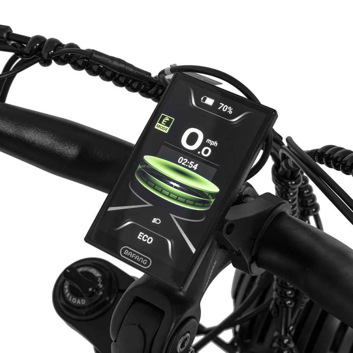 A close-up of an electric bike’s handlebar display showing speed, battery level, mode (ECO), and other ride information, with wires and controls visible around the display.