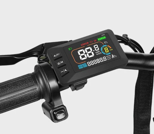 Close-up of an electric bike handlebar showing a digital display screen with speed, battery level, and control buttons. The display reads 00.0 mph and shows various status icons and indicators.