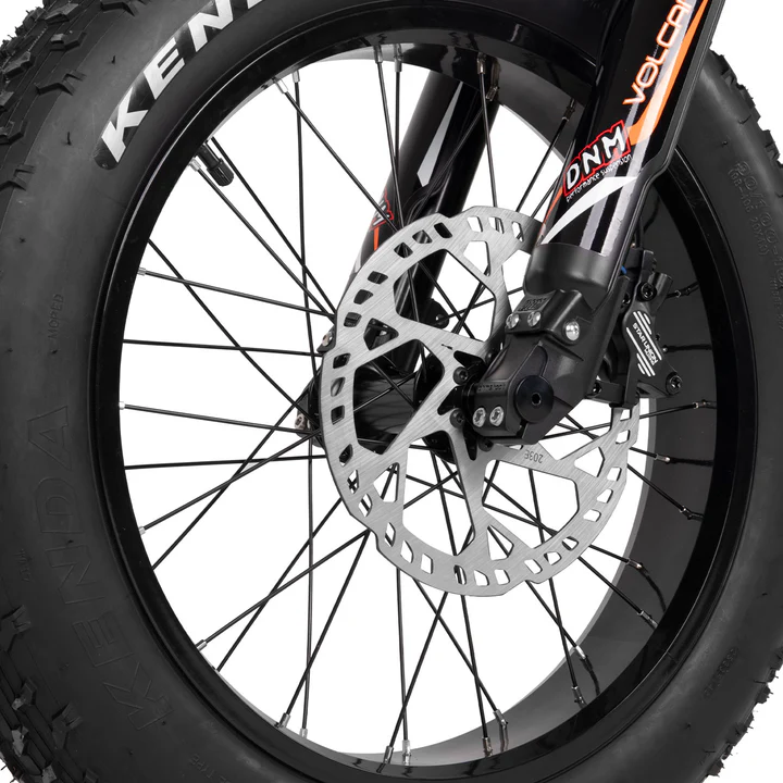 Close-up of a bicycle front wheel with a disc brake system, showing the tire tread, spokes, and brake rotor, as well as part of the fork with visible brand logos.